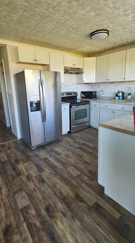 a kitchen with granite countertop white cabinets and stainless steel appliances