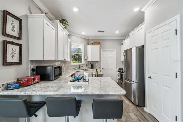 a kitchen with stainless steel appliances granite countertop white cabinets and a stove top oven