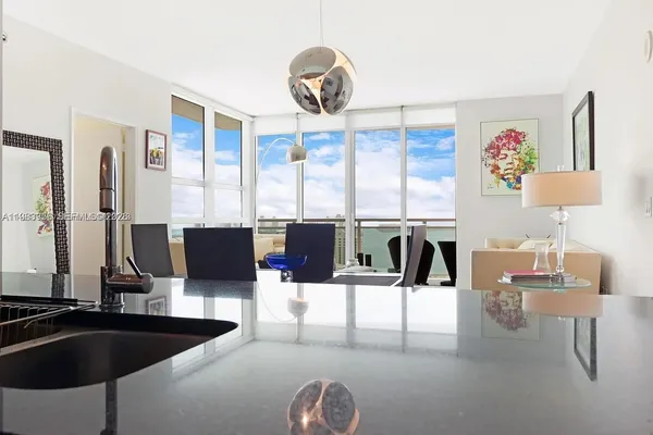 a living room with stainless steel appliances kitchen island granite countertop a table and chairs