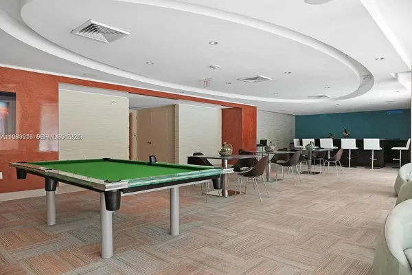 a room with furniture pool table and chairs