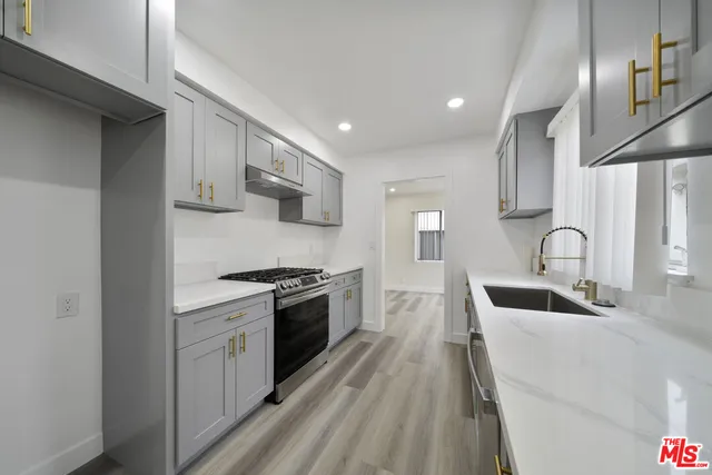a kitchen with stainless steel appliances a sink cabinets and wooden floor