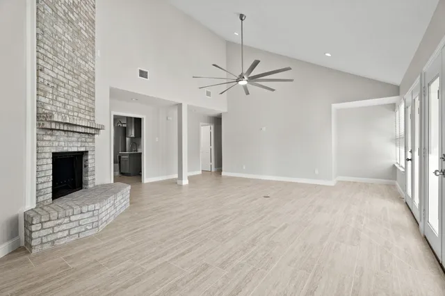 a view of an empty room with wooden floor fireplace and a window