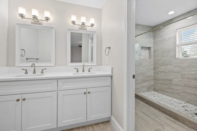 a bathroom with a double vanity sink a mirror and a shower