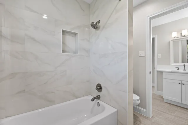 a bathroom with a tub shower vanity and a sink