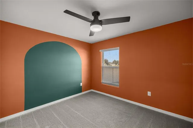 an empty room with a window and ceiling fan