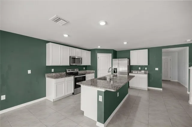 a kitchen with stainless steel appliances kitchen island granite countertop a refrigerator and a stove top oven
