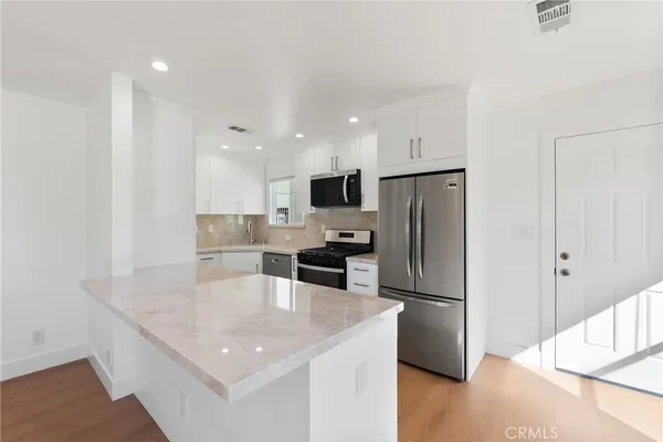 a kitchen with stainless steel appliances granite countertop a refrigerator a sink a stove a microwave and a refrigerator