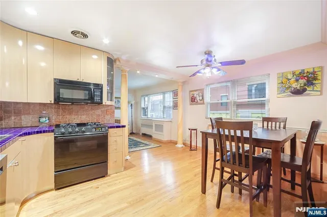 a kitchen with stainless steel appliances granite countertop a stove top oven a sink dishwasher and a dining table with wooden floor