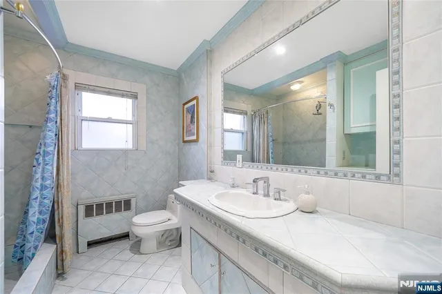 a bathroom with a granite countertop sink a toilet a mirror and a tub
