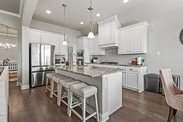 a kitchen with stainless steel appliances granite countertop a sink stove refrigerator and cabinets