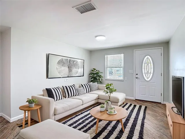 a view of an empty room with wooden floor and a window