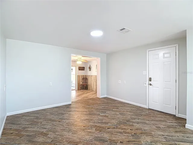a view of a livingroom with a fireplace a chandelier fan and wooden floor