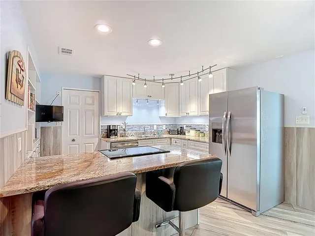 a kitchen with kitchen island granite countertop a sink a counter space appliances and cabinets