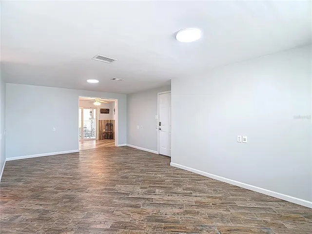 a view of an empty room with wooden floor and window