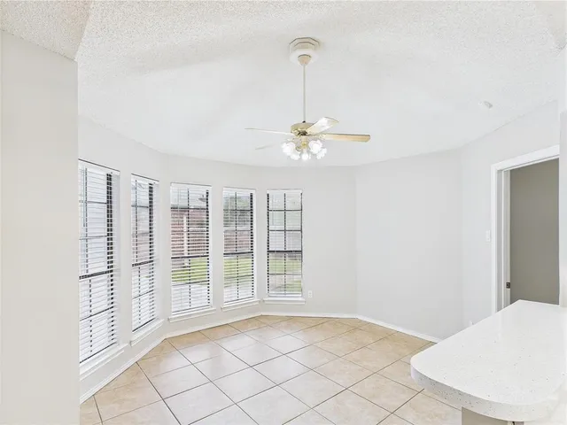 a view of an empty room with chandelier fan