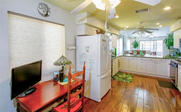 a kitchen with stainless steel appliances granite countertop a refrigerator a stove a sink dishwasher and a dining table with wooden floor