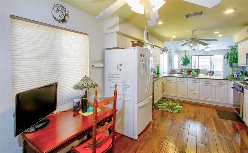 6502 River Run Boulevard, Unit 6502 Weeki Wachee, FL 34607 - Photo 7 of 47 a kitchen with stainless steel appliances granite countertop a refrigerator a stove a sink dishwasher and a dining table with wooden floor