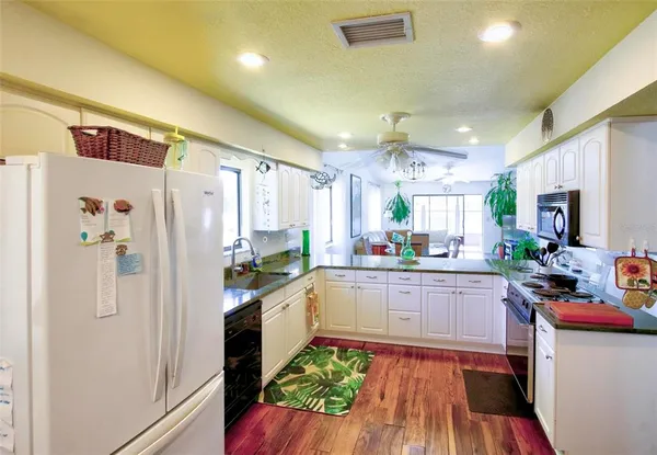 a kitchen with stainless steel appliances a refrigerator a sink dishwasher a stove and white cabinets with wooden floor