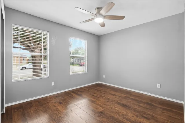 a view of empty room with wooden floor and fan