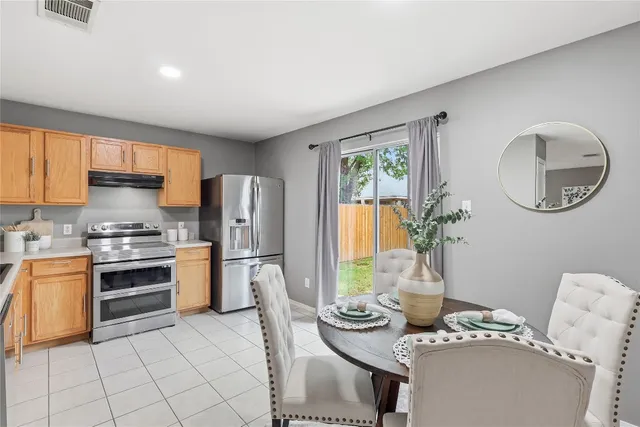 a kitchen with stainless steel appliances granite countertop a stove a refrigerator a sink dishwasher a dining table and chairs with wooden floor