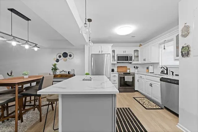a large white kitchen with lots of counter space a sink appliances and cabinets