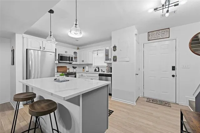 a kitchen with stainless steel appliances a stove a refrigerator and white cabinets with wooden floors