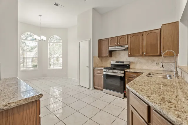 a kitchen with granite countertop a sink cabinets and stainless steel appliances