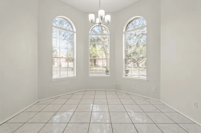 a view of an empty room with window and chandelier fan