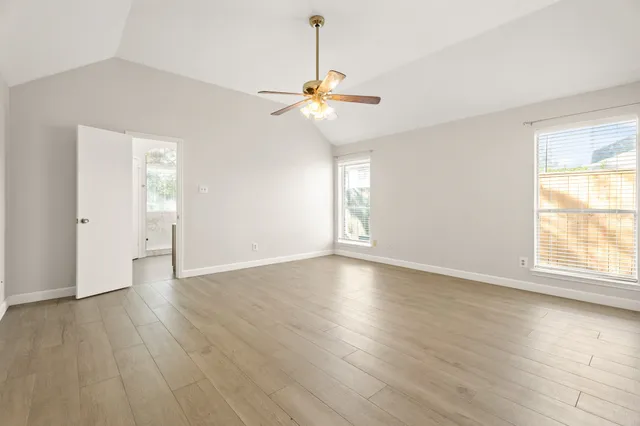 a view of an empty room with window and wooden floor