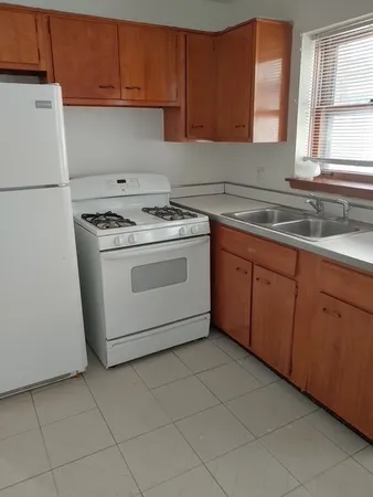 a kitchen with granite countertop a sink a stove a refrigerator and cabinets