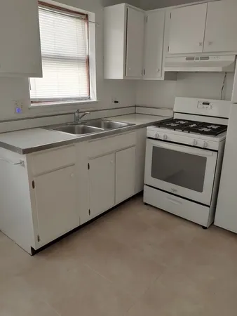 a kitchen with granite countertop white cabinets and white stainless steel appliances