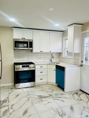 a kitchen with stainless steel appliances granite countertop a stove a sink and a microwave