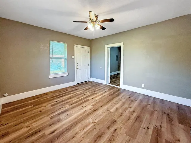 a view of empty room with wooden floor and fan