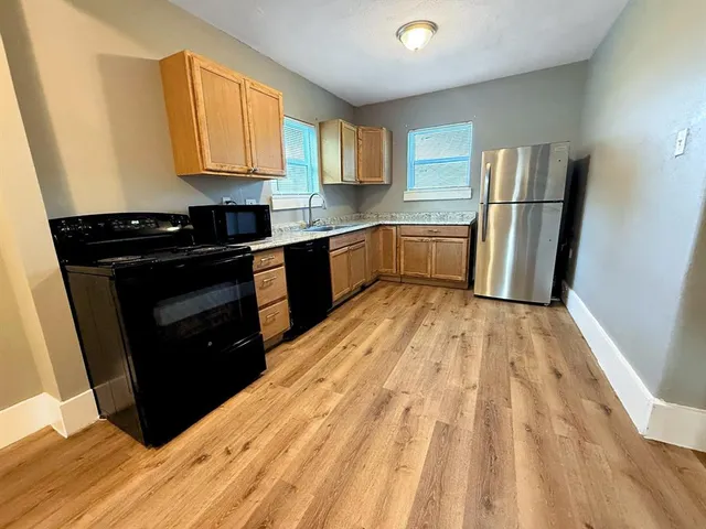 a kitchen with a sink a refrigerator freezer a stove and a window