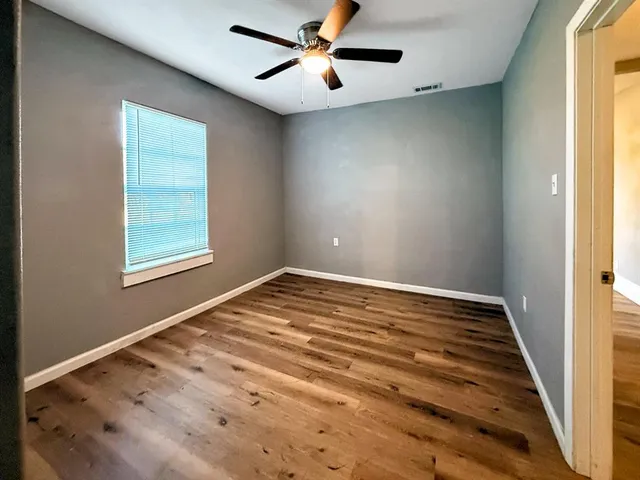 a view of empty room with window and ceiling fan