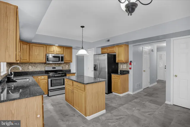 a kitchen with stainless steel appliances granite countertop a sink a stove and refrigerator