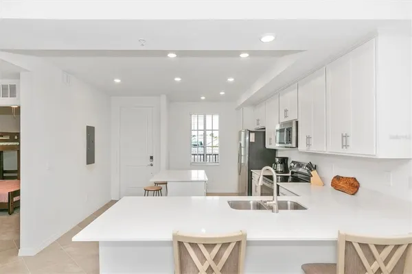 a kitchen with stainless steel appliances a sink a stove a refrigerator cabinets and a dining table