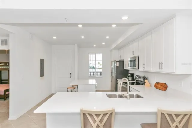 a kitchen with stainless steel appliances a sink a stove a refrigerator cabinets and a dining table