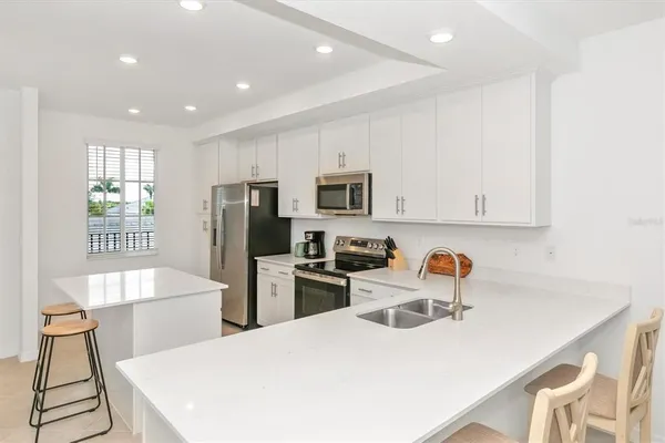 a kitchen with stainless steel appliances a sink a stove a refrigerator cabinets and a dining table