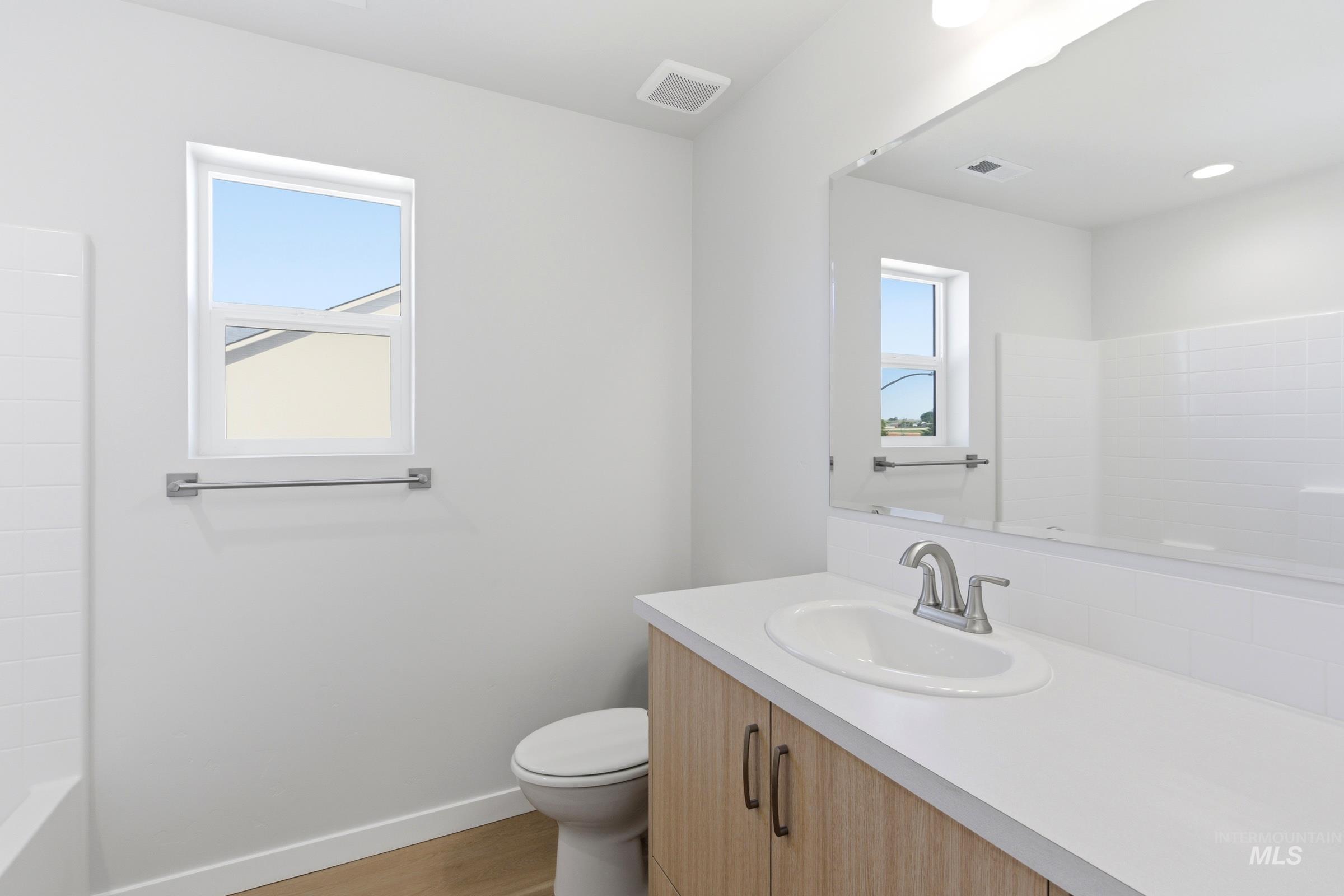 13677 Redway Court Caldwell, ID 83607 - Photo 22 of 35 Bathroom featuring a light wood-finish vanity with a white countertop and integrated sink, brushed nickel faucet, and a large wall mirror