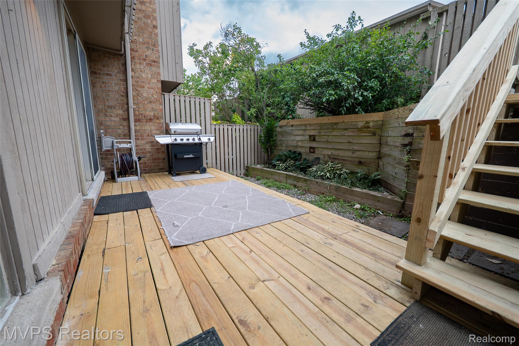 804 Oak Brook Ridge Drive, Unit 149 Rochester, MI 48307 - Photo 3 of 46 Expansive wood deck with a privacy fence, brick exterior, and multi-level landscaping