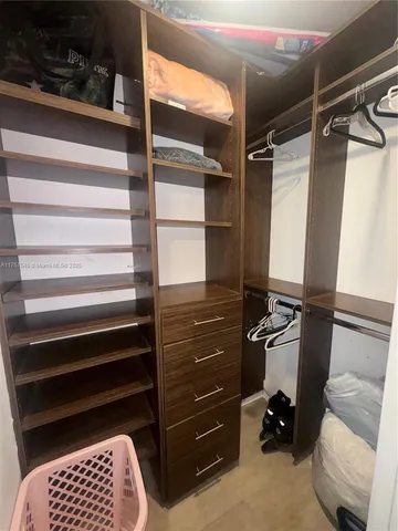 a view of walk in closet with clothes and shoes