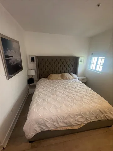 a large bed sitting in a bedroom next to a window