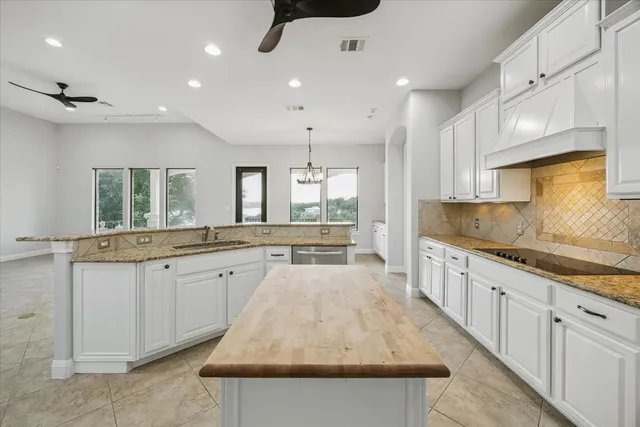 a large kitchen with kitchen island a sink a center island stainless steel appliances and a window