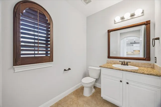 a bathroom with a granite countertop toilet a sink and a mirror