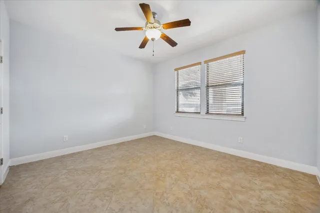 an empty room with ceiling fan and window