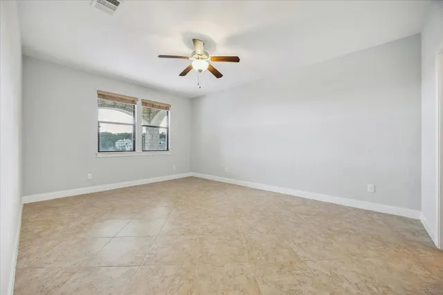 an empty room with windows and fan
