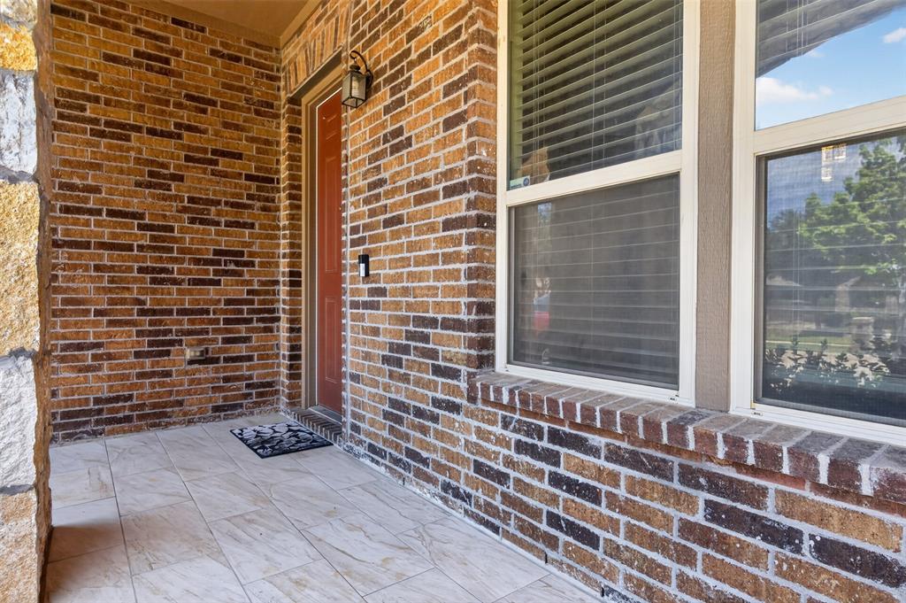 8728 Maple Ridge Trail Fort Worth, TX 76244 - Photo 38 of 40 Covered entry featuring a paneled front door, exterior wall lantern, and brick facade