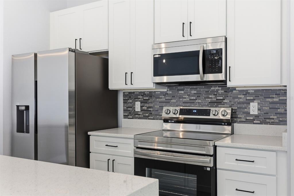 4487 Southwest 152nd Street Ocala, FL 34473 - Photo 14 of 41 a kitchen with stainless steel appliances a stove and a refrigerator with white cabinets