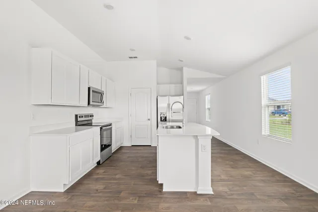 a kitchen with cabinets and wooden floor